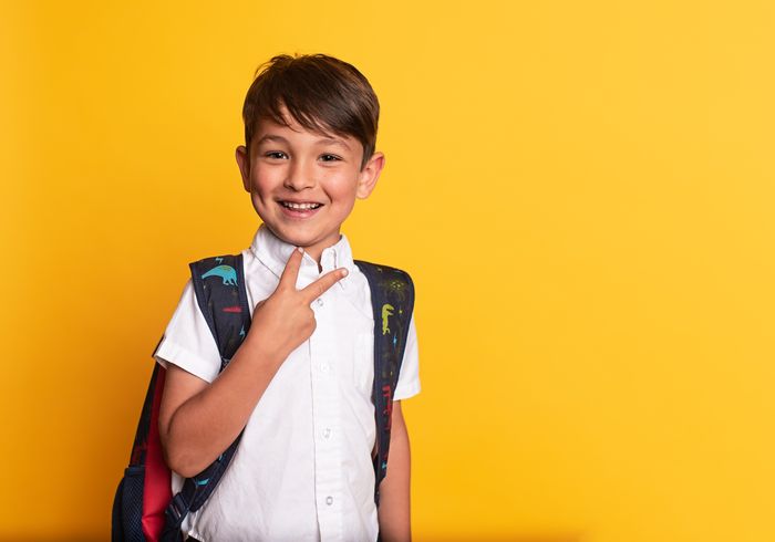 A smiling school-age child with a backpack